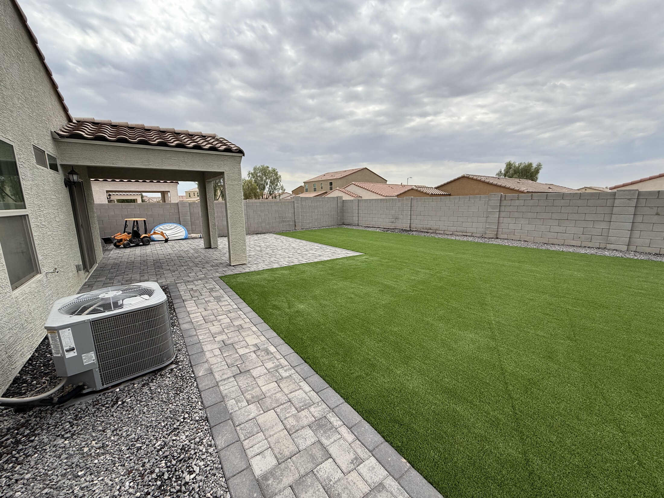 Backyard with paver side path, covered patio, and large turf area