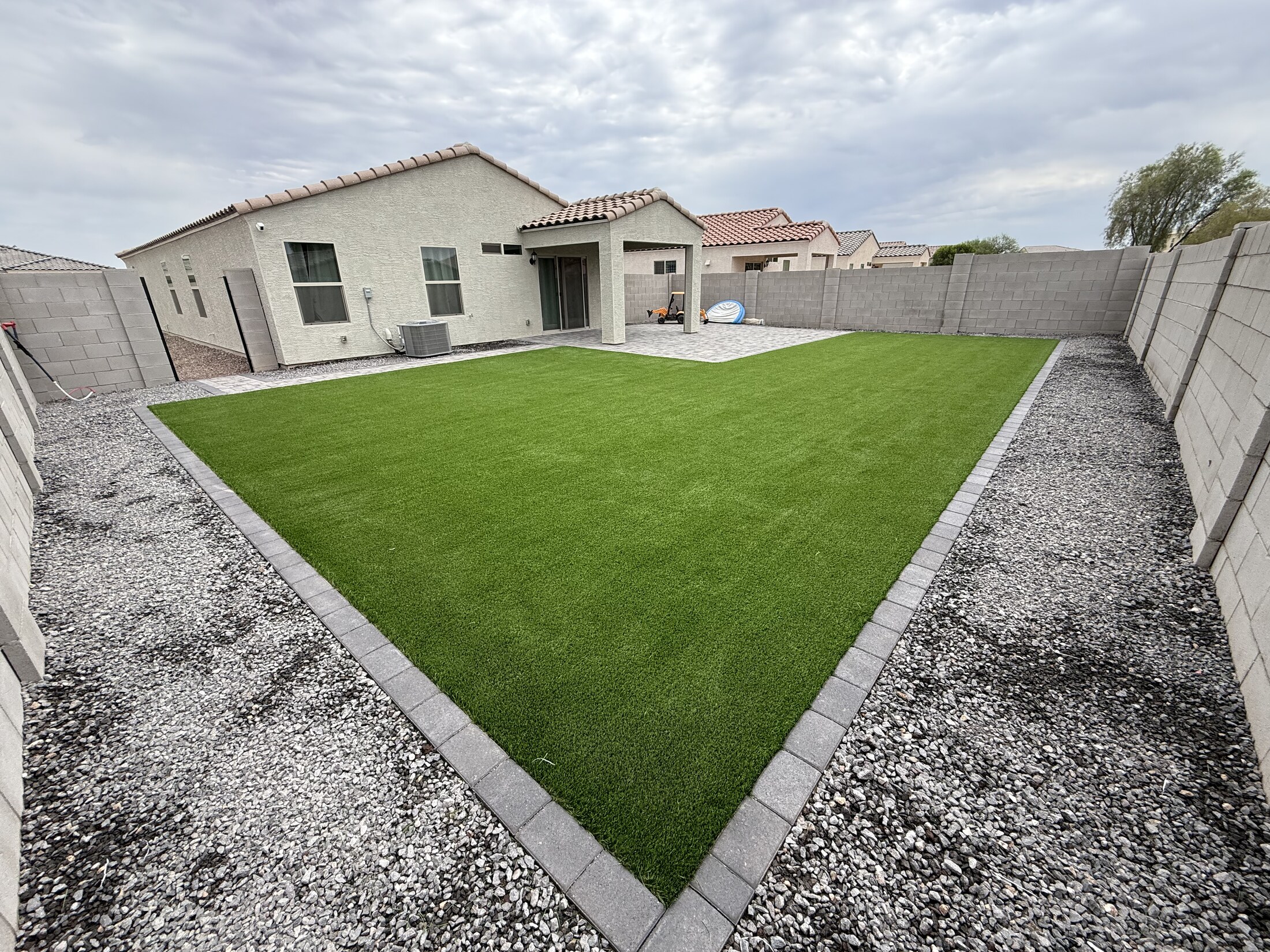 Large triangular turf section framed by pavers and gravel