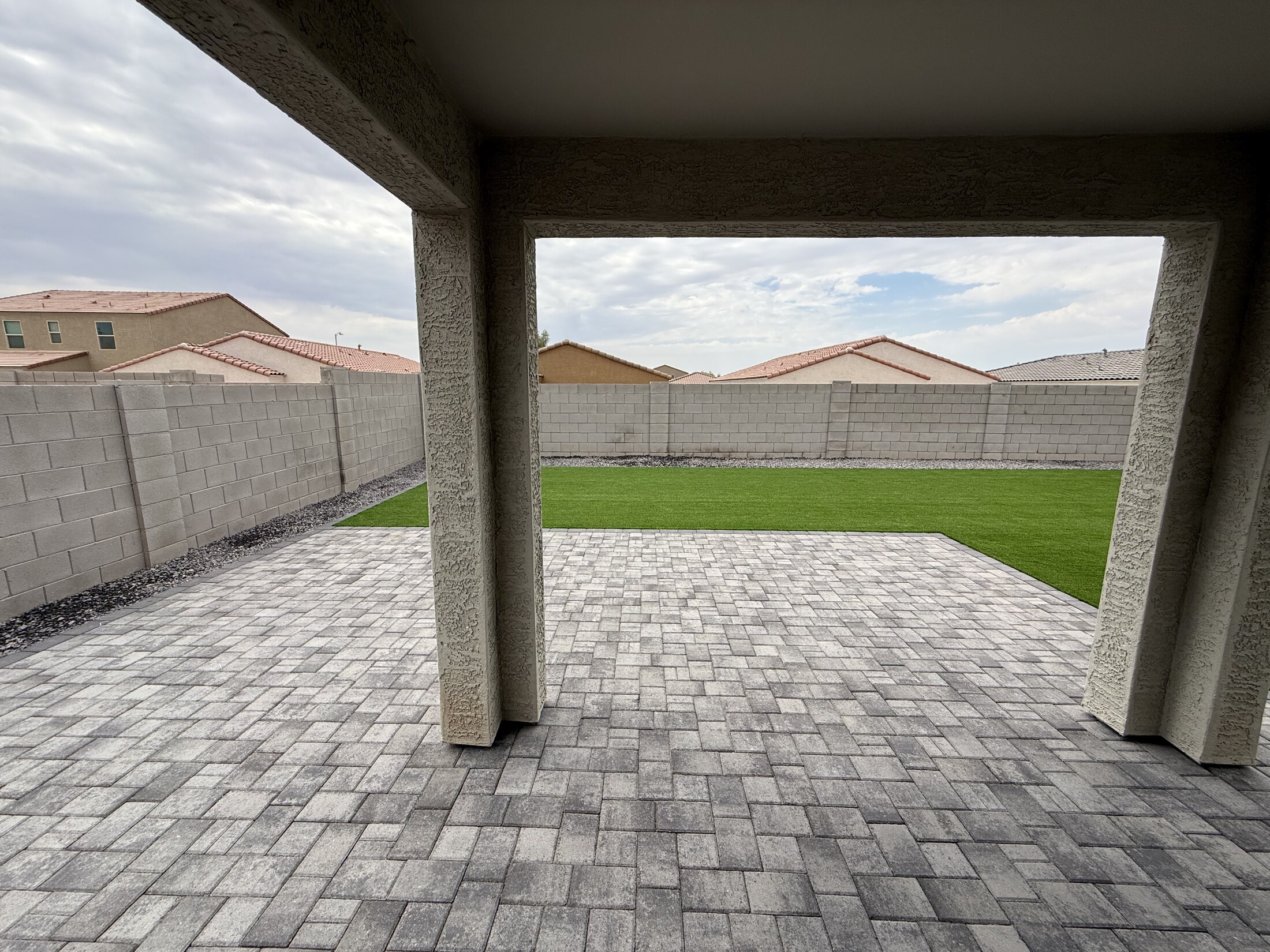 Paver patio and turf backyard under an overcast sky