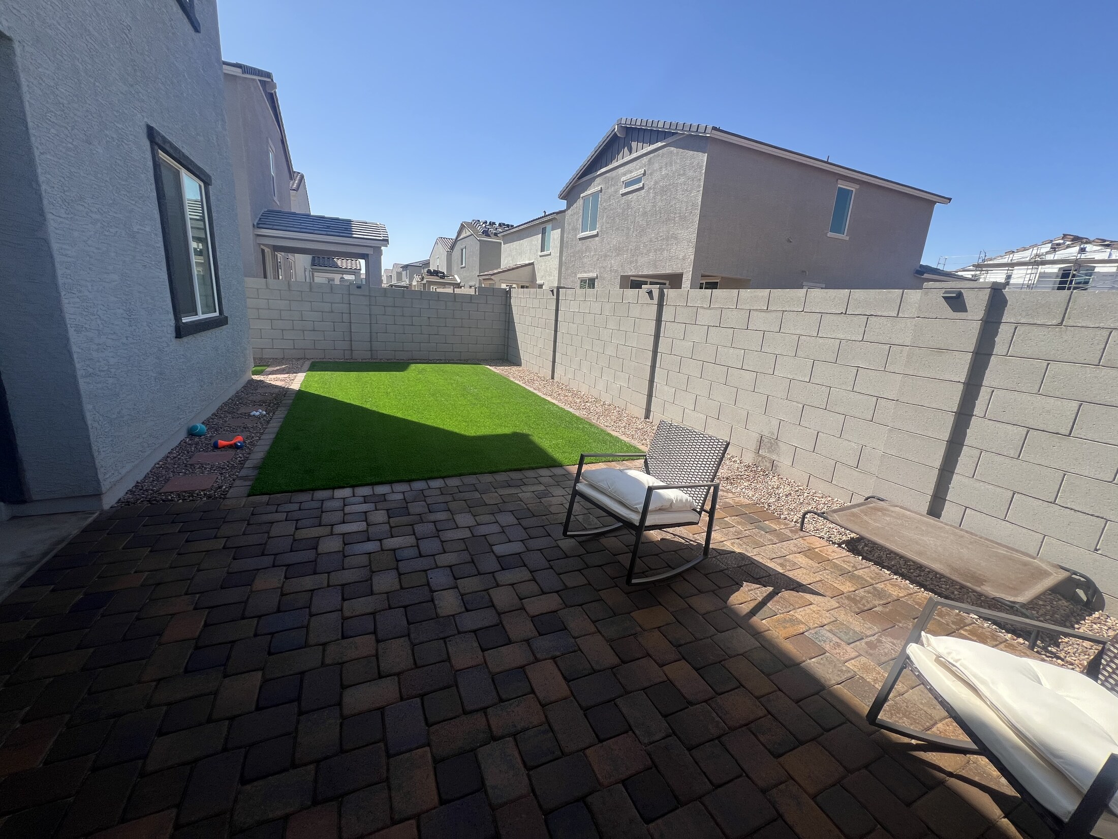 Backyard with turf strips, pavers, and gravel around a covered patio