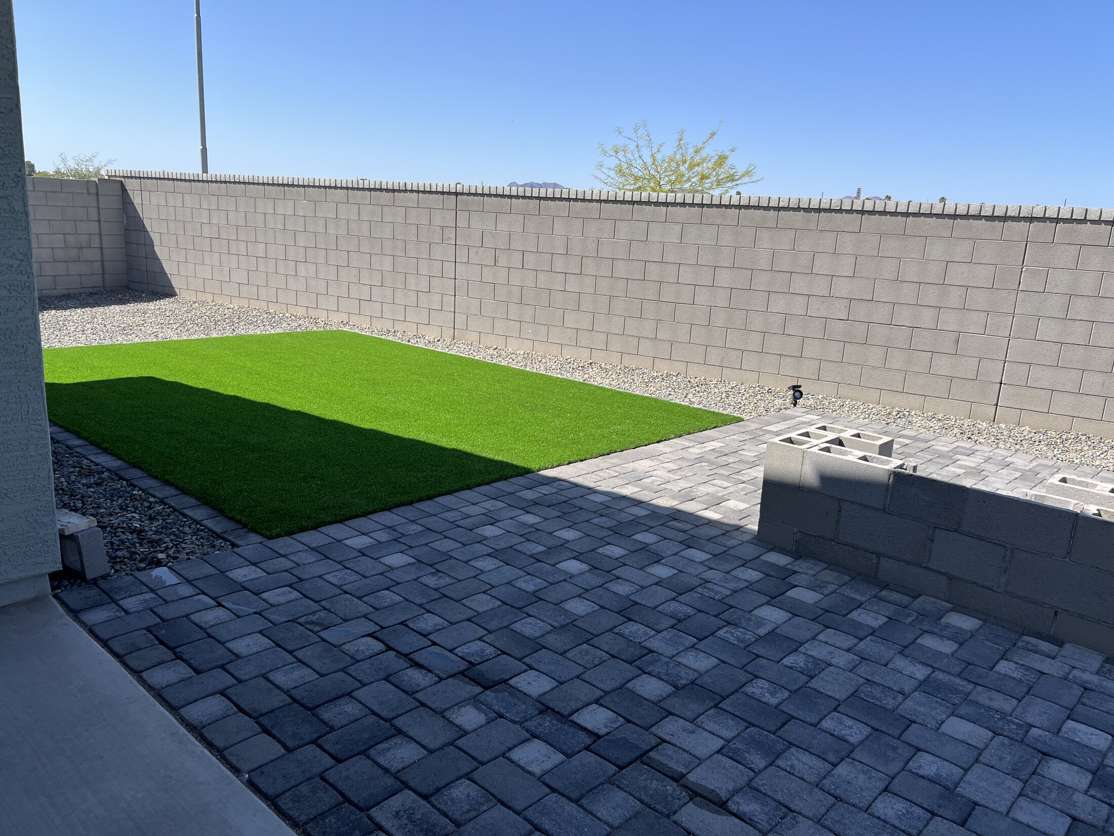Backyard with broad paver surface, gravel border, and defined edge layout