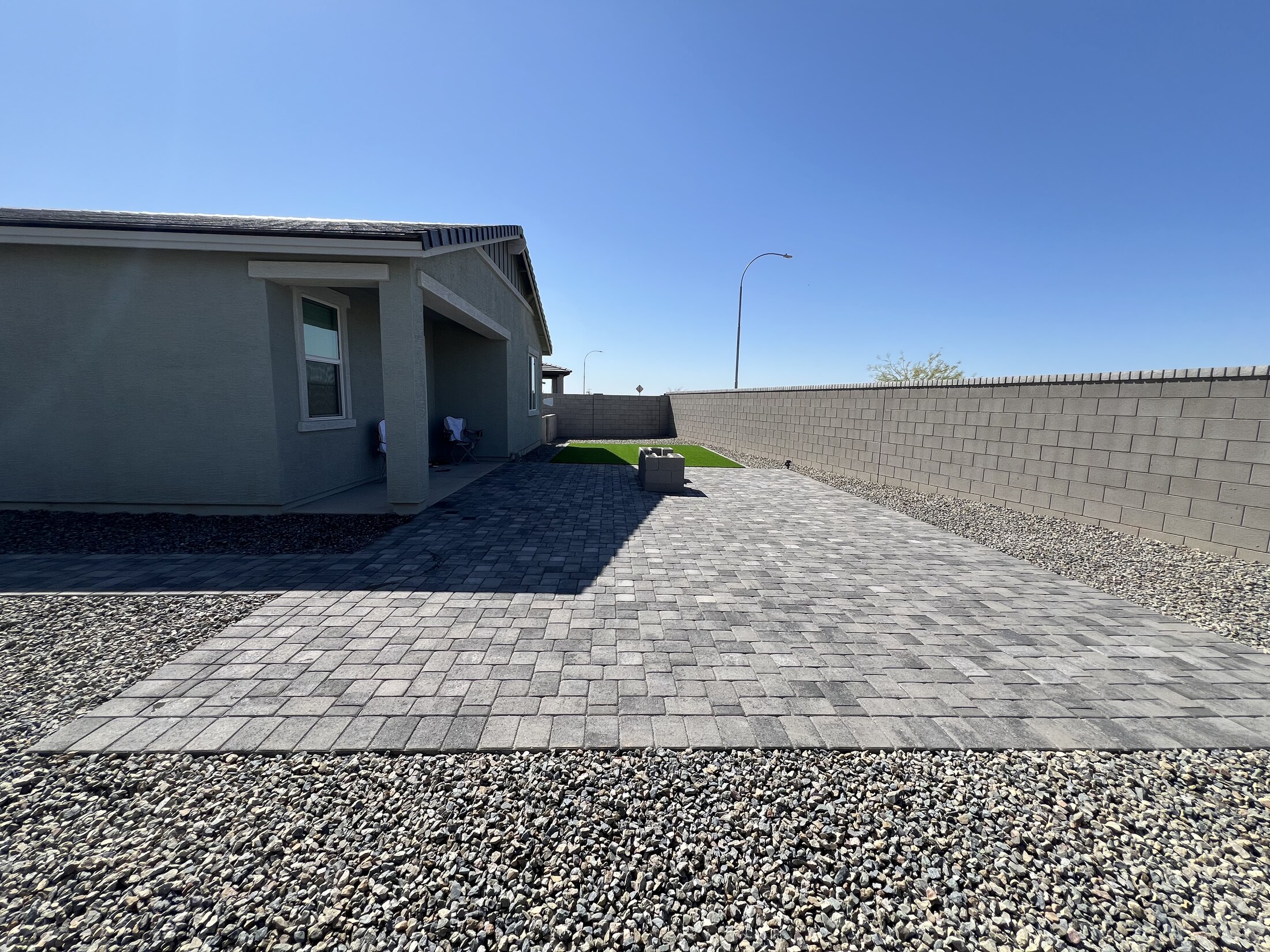 Large paved rear yard with gravel border and small turf area