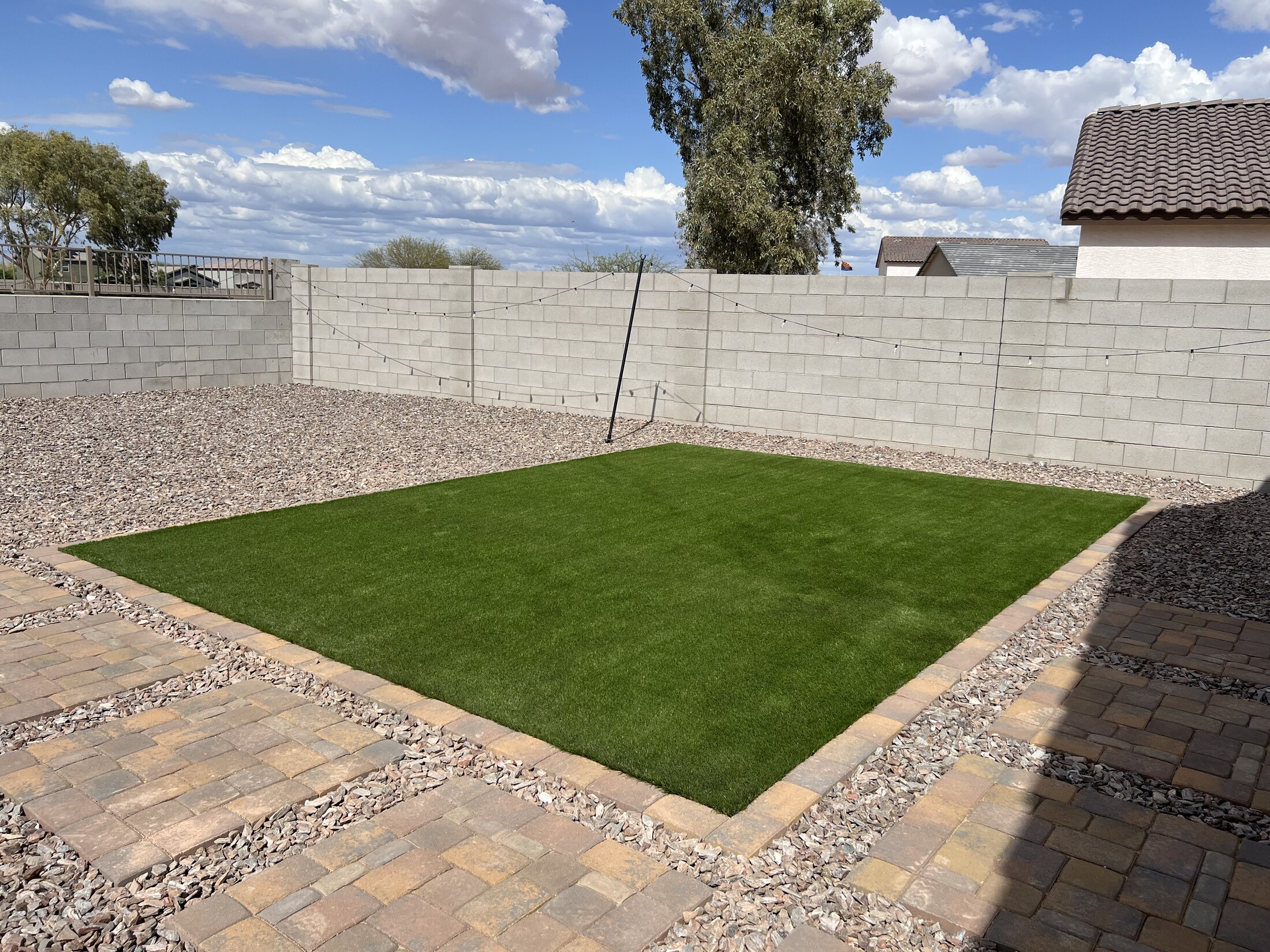 Square turf area bordered by pavers and gravel