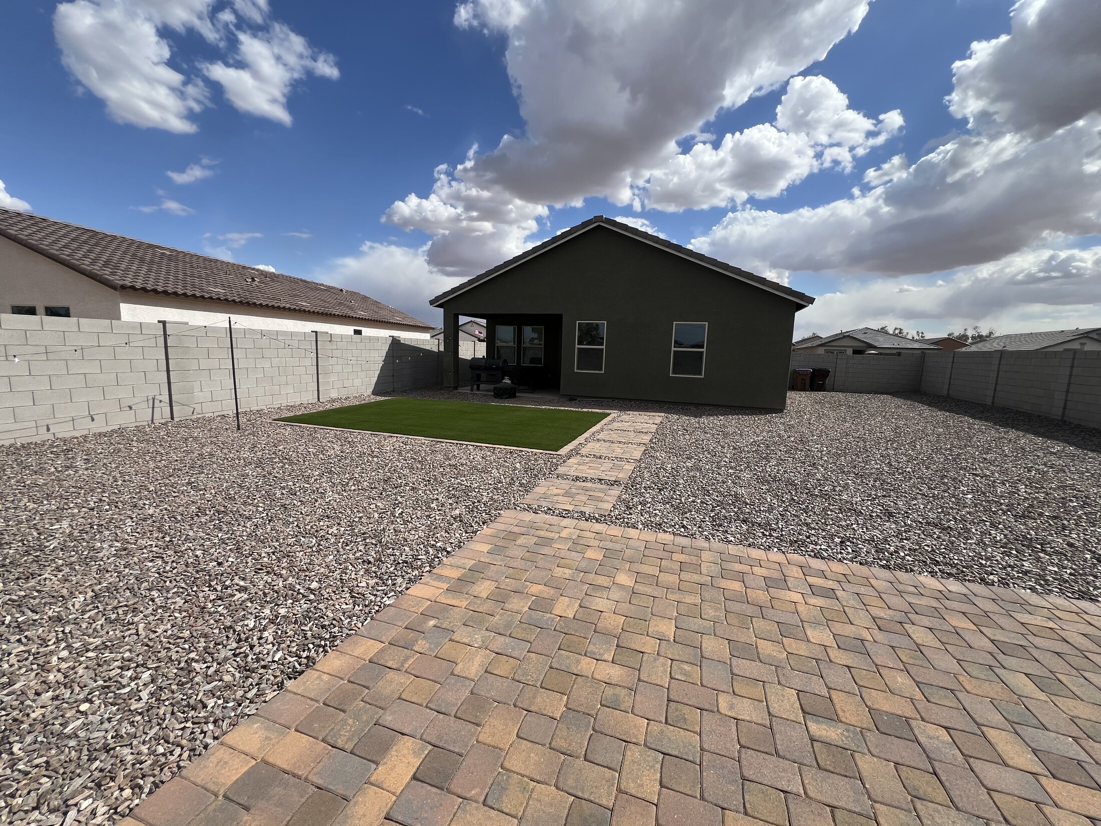 Paver walkway leading to a turf patch in a large gravel yard